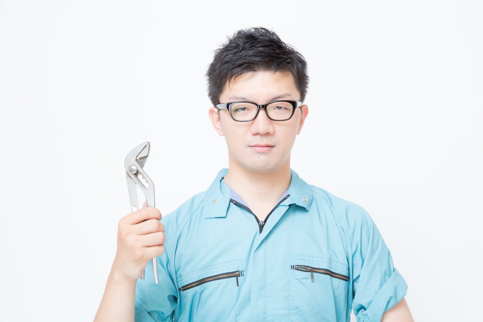 プライヤーを握って立つ作業着姿の眼鏡をかけた男性［モデル：OZPA］
