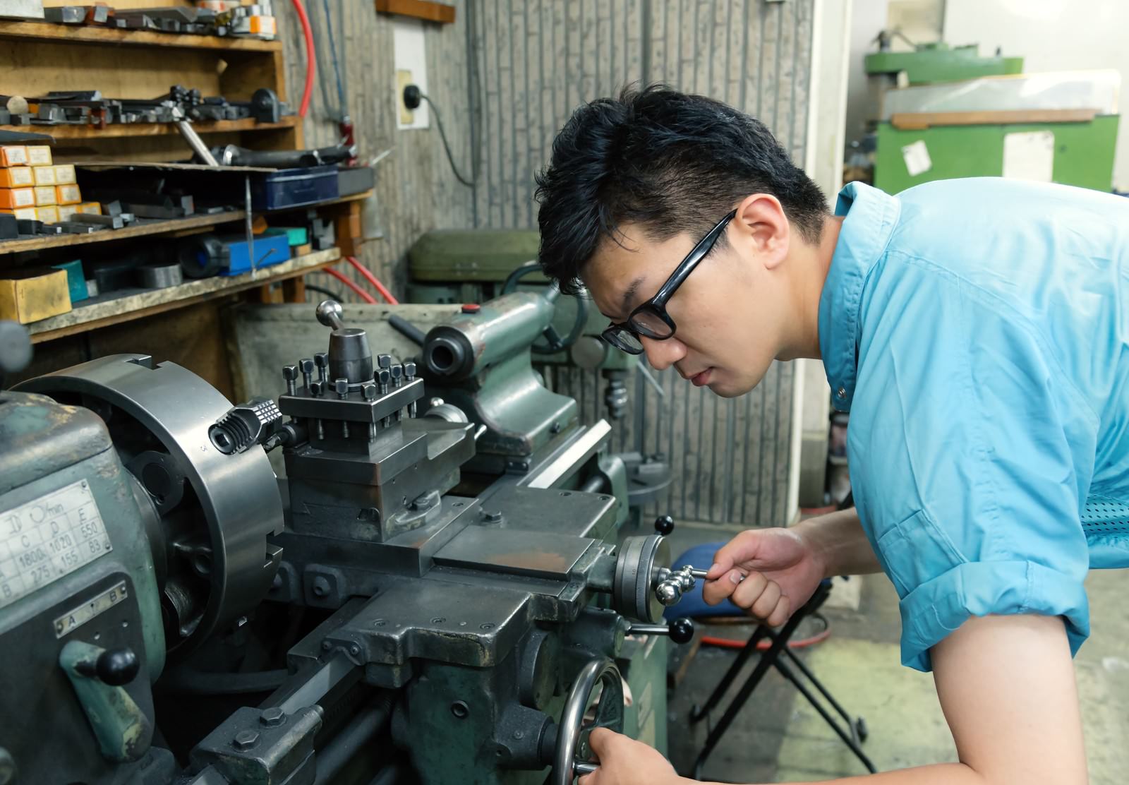 旋盤のハンドルを調整する作業着の男性［モデル：OZPA］