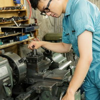 旋盤のバイトホルダーを調整する作業員の写真