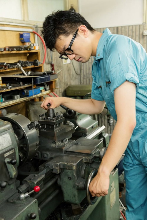 旋盤のバイトホルダーを調整する作業員