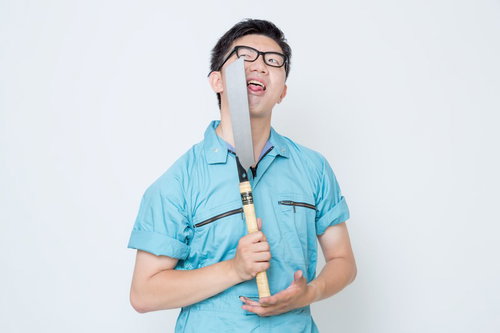 ノコギリを顔の前に立てる作業服の男性