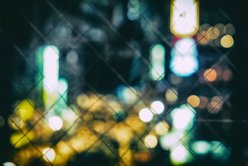 フェンスごしに見たボケた繁華街の夜景