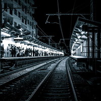 終電間際、混雑する駅ホームの線路沿い、乗客待機の風景の写真