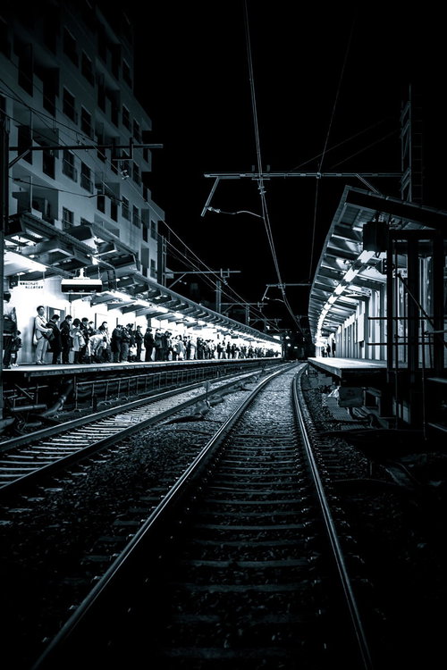 終電間際、混雑する駅ホームの線路沿い、乗客待機の風景