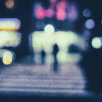 夜間のコンビニ前の横断歩道でぼけた光が映る風景の写真