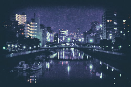 日も落ちた都会の河川に映るビル群の夜景と水面反射