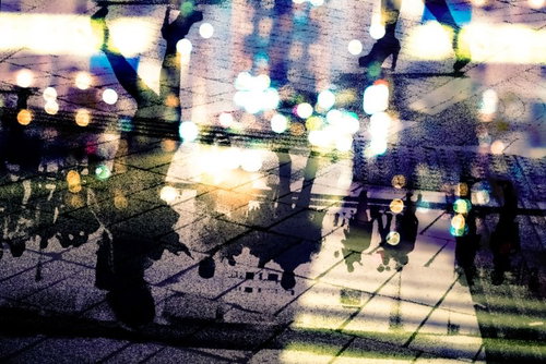 都会の夜間の人混みを映すアスファルト（フォトモンタージュ）