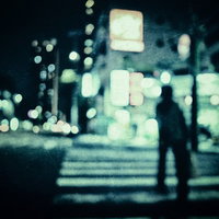 深夜の横断歩道を渡る人影のシルエット、街路灯の光に照らされの写真