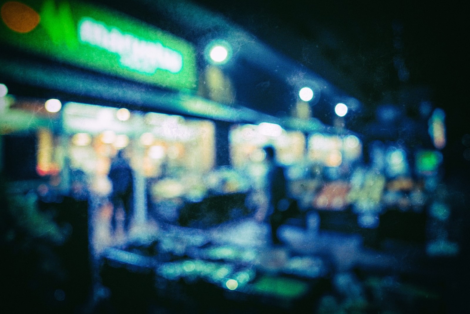 夜間営業のスーパーの外観が光のボケで映った風景