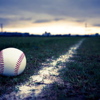 硬球とグラウンドのライン、夕焼け空を背景にした野球グラウンドの写真