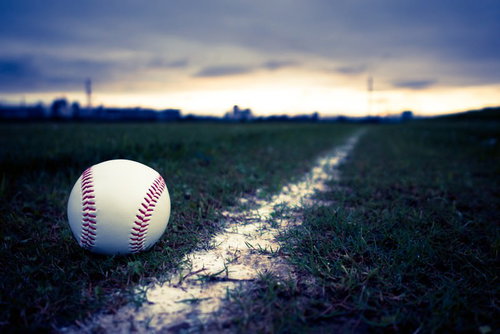 硬球とグラウンドのライン、夕焼け空を背景にした野球グラウンド