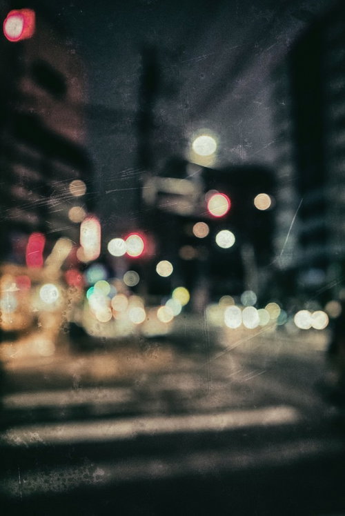 ピンボケの夜の街並み 深夜の光と雨に濡れた暗い路面