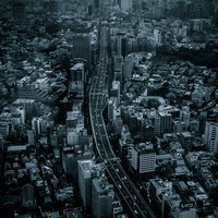 雨の都会に立ち並ぶビル群と幹線道路を走行する車群の写真