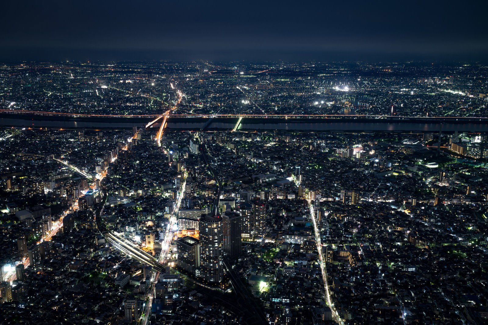 川に架かる橋がライトアップされた都会の夜景を空から撮影した写真