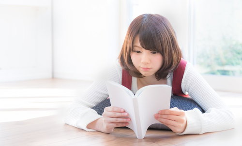 休日を読書で過ごす女性、リビングで本を読む