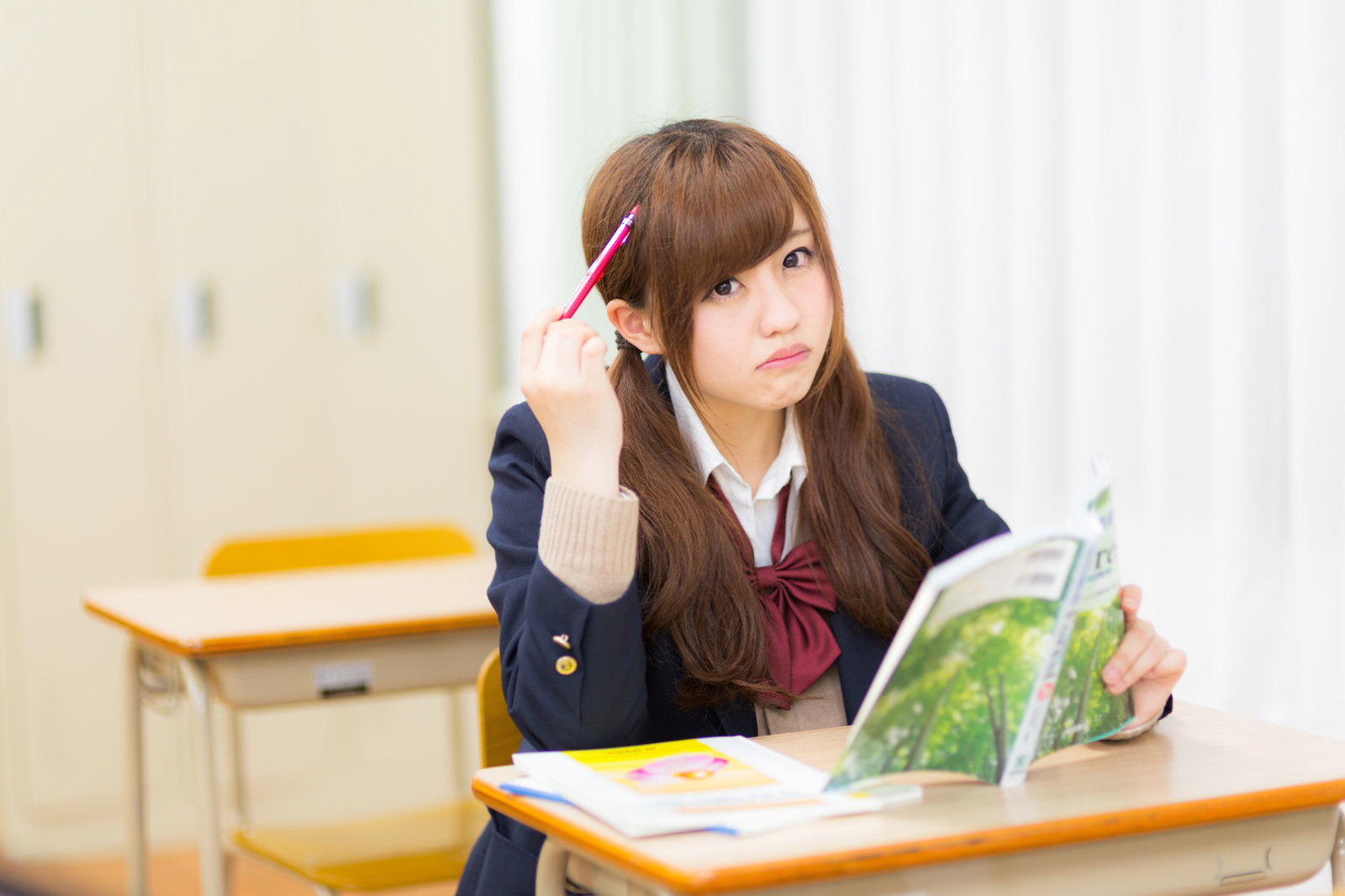 教室で教科書を開きペンを持って考える女子高生［モデル：河村友歌］