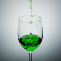 グラスに注がれた緑色の液体が渦巻く不気味なポイズンの写真