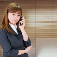 オフィスで携帯電話を耳に当てるスーツの女性の写真