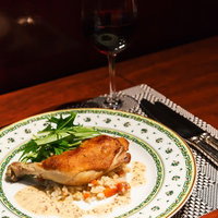 鶏もも肉のコンフィとワイングラスの写真