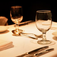 白いクロスの上の銀のカトラリーとグラスの写真