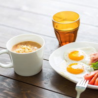 朝食のワンプレートに目玉焼きとスープ、生ハムとトマトの写真