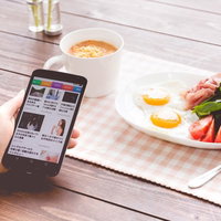 朝食を食べながらスマートニュースをチェックする女性の写真