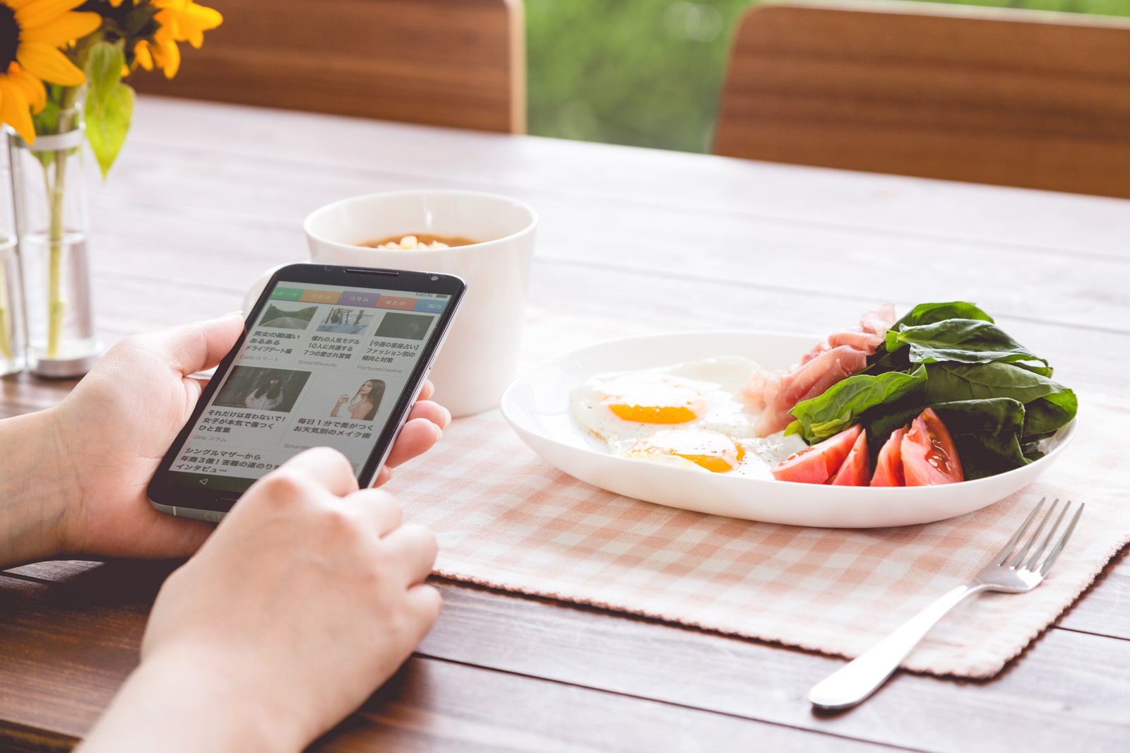ホテルの朝食でスマートニュースを見ながら食事をする女性