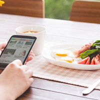 ホテルの朝食でスマートニュースをチェックする女性の写真