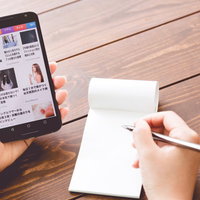 スマートニュースアプリでコラムをチェックしながらメモを取るの写真