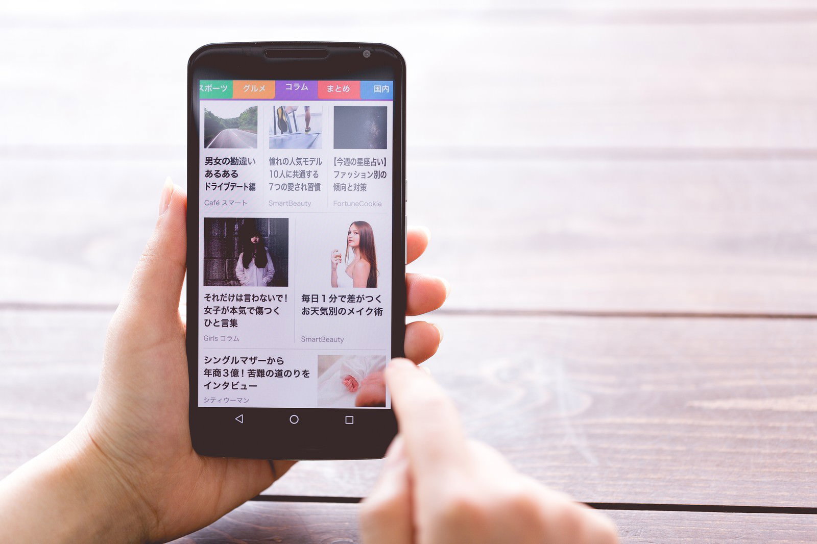木目テーブルの上でスマートニュースを開くスマホ