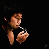 暗いBARでタバコに火をつける男性の写真