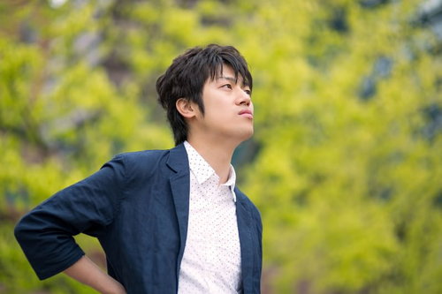緑の中で背筋を伸ばす若い男性