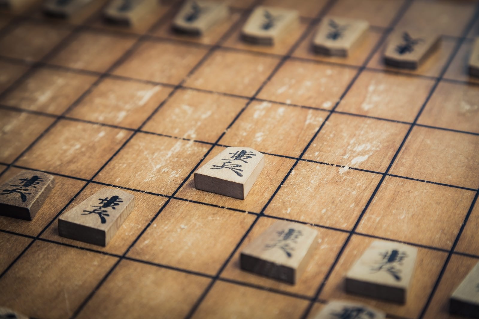 将棋盤に置かれた駒。白い駒に黒い文字が彫られている