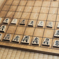 これから始まる将棋の対局、木製盤に初期配置された駒たちの写真