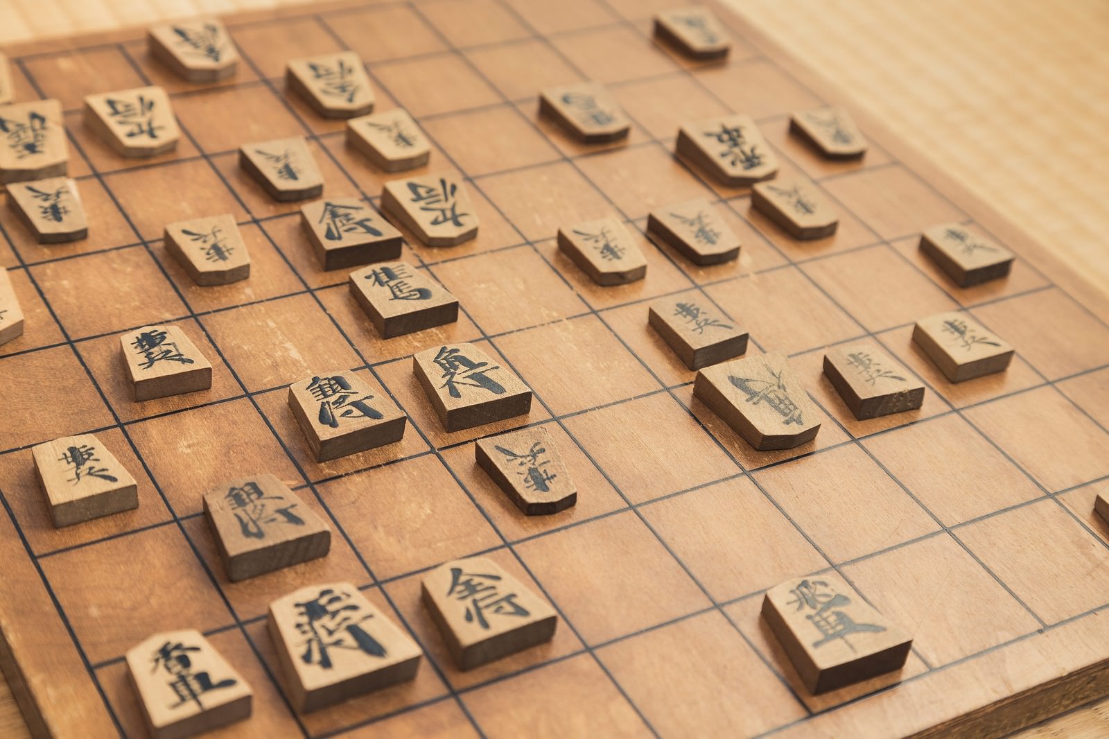 将棋の盤上に木製の駒が並べられた対局風景