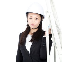 白いヘルメットを被ってスーツで脚立を運ぶ庶務課の女性の写真