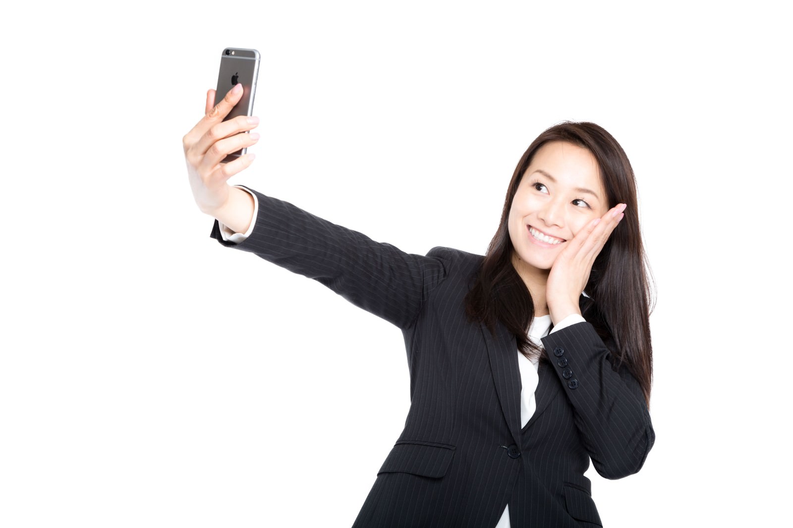 スマートフォンを手に自撮りしながら歯痛ポーズをする紺色スーツの女性社員［モデル：土本寛子］