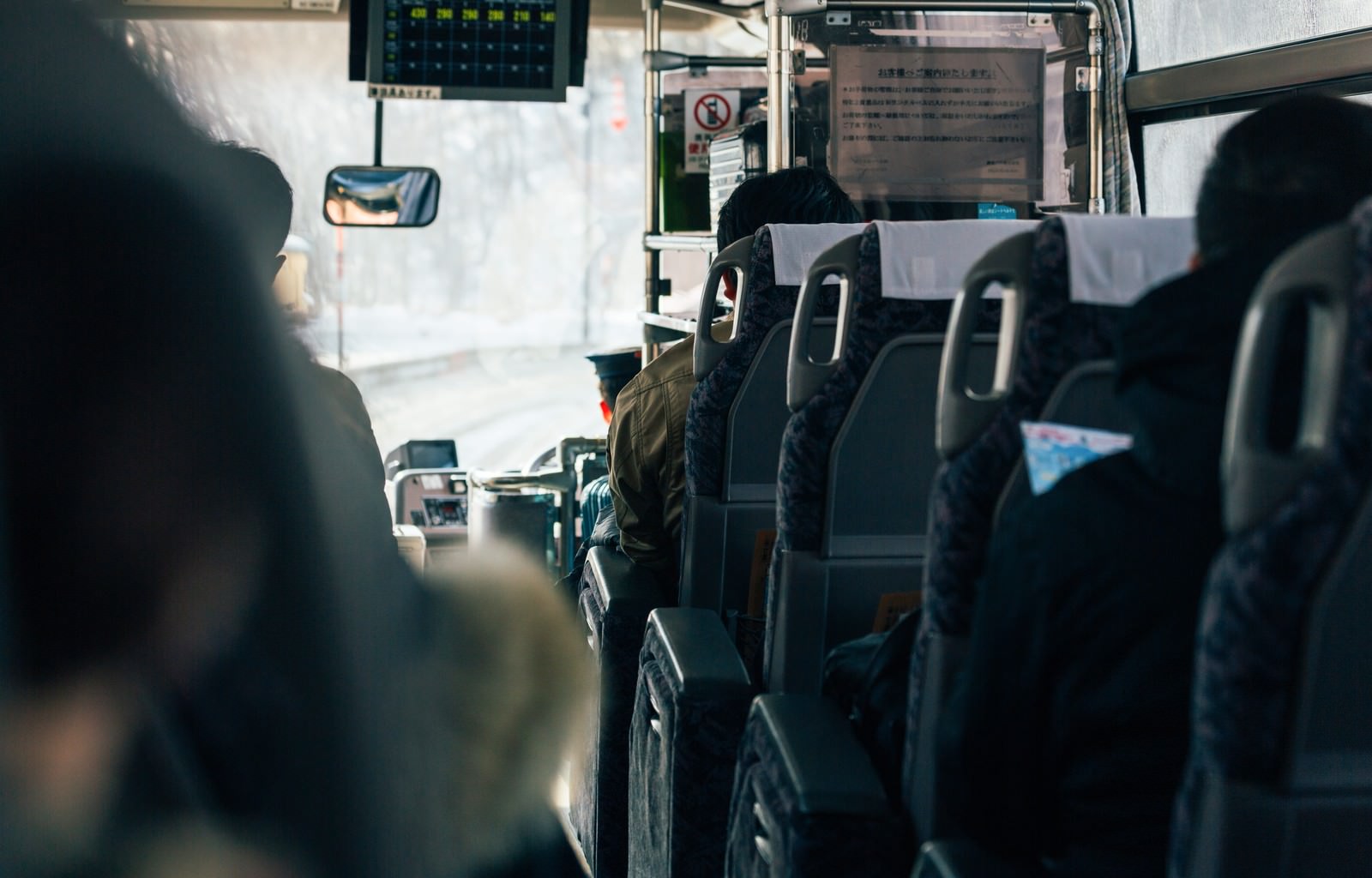 高速バスの車内。黒いシート座席と運転手席、窓からの日光が見える