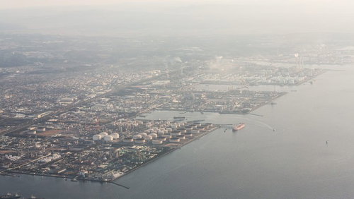 スモッグに覆われた工業地帯と港湾施設の航空風景