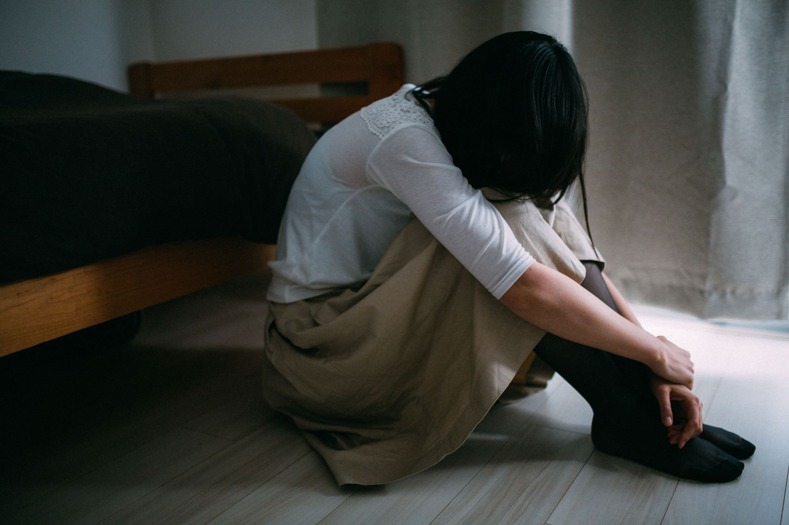 失恋で床に座り込み、膝を抱えてうつむく女性［モデル：たけべともこ］