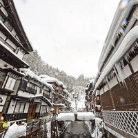 雪が降る銀山温泉の伝統的な木造建築の写真