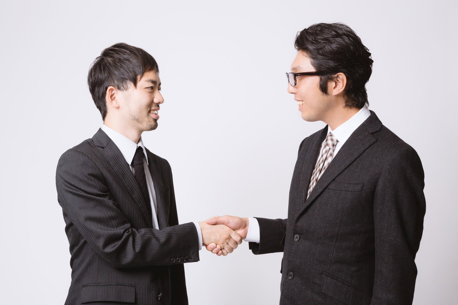 紺色のスーツを着た2人の男性が笑顔で握手している［モデル：ひろゆき  紳さん］