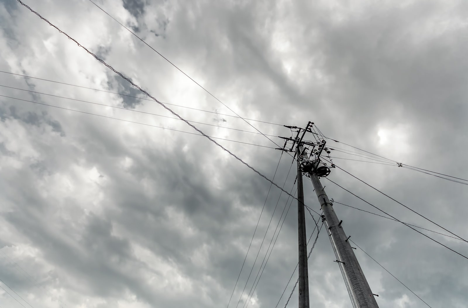 電柱と電線が走る曇った空。暗い雲に包まれている。