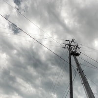 曇り空に立つ電柱と電線の写真