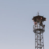 曇り空に立つ火の見櫓とスピーカーの写真