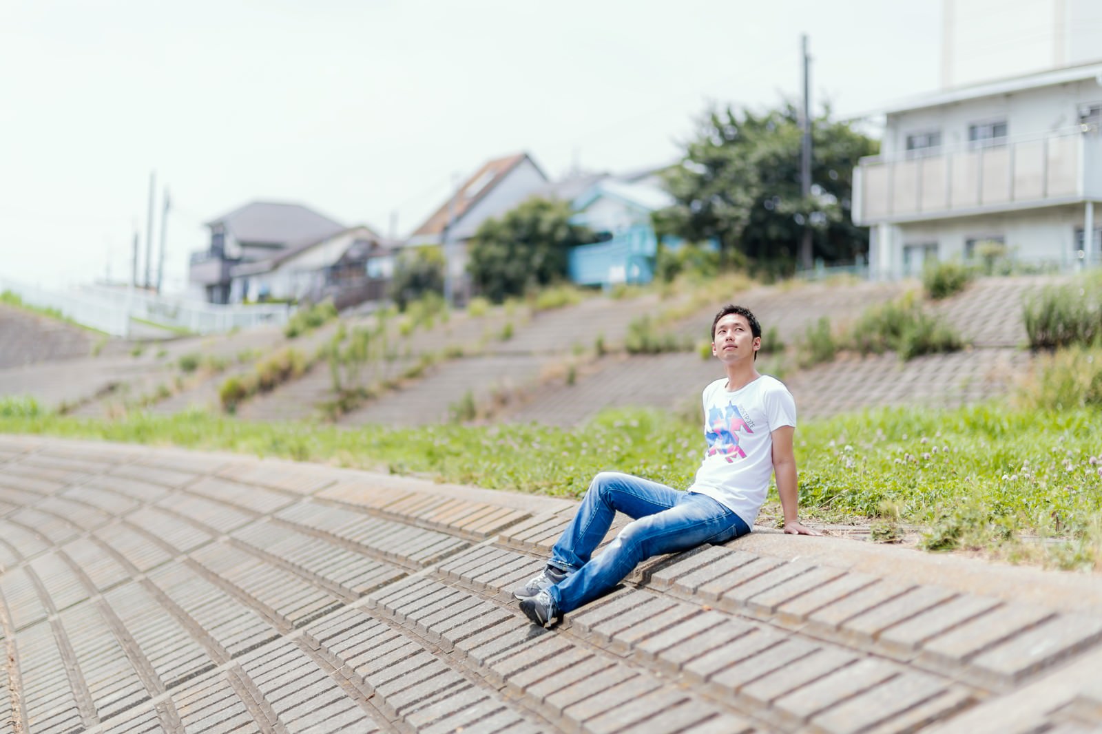 土手に座って日向ぼっこする男性［モデル：大川竜弥］