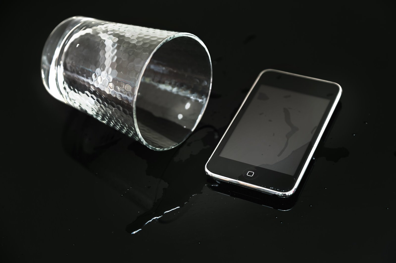 倒れたグラスからこぼれた水とスマホ
