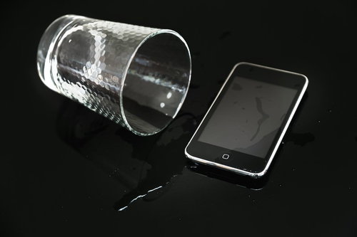 倒れたグラスからこぼれた水とスマホ