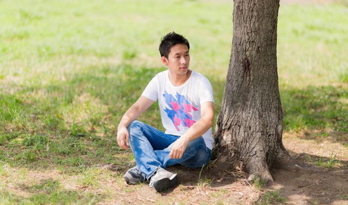 公園の木陰でくつろぐ若い男性