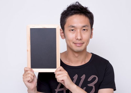 小さな黒板を持って見せる男性